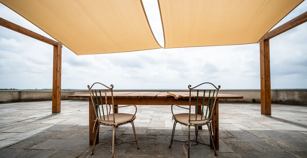 Mesa y sillas bajo toldo a dos aguas con laterales abiertos
